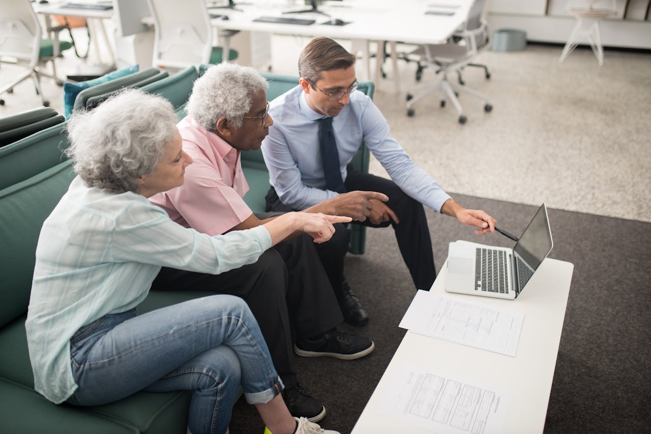 Senior couple consulting with a professional on a laptop in a modern office setting.